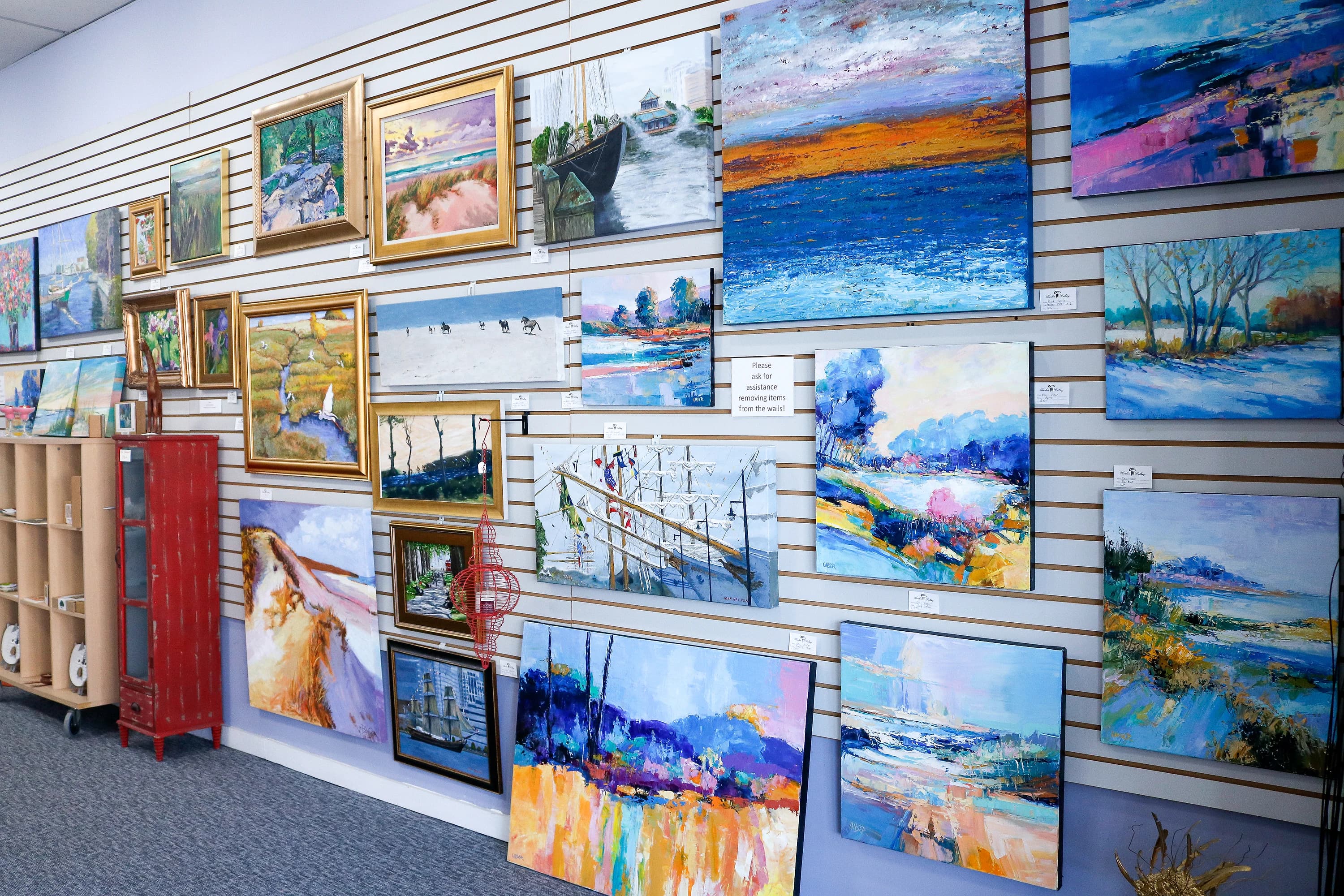 Gallery wall of seascape paintings under warm pendant light